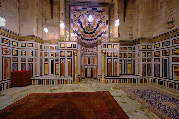 The back wall is covered in marble paneling; the middle is a square of inlaid white and red marble in a geometric pattern of Syrian style.