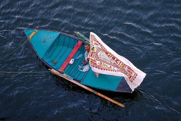 Local entrepreneur ties up to our ship and hopes to exchange fabric for cash.