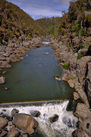 The gorge walls are dolerite, a hard, dark, crystalline igneous rock that forms prominent columns and cliffs.