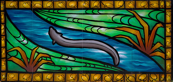 The street art work represents an eel swimming through a waterway surrounded by fields of flax.