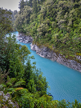 Glacial melt carries rock flour into the river, scattering sunlight that gives the water its vivid turquoise‑blue hue.