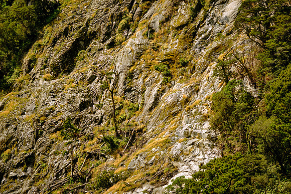 Hanging valleys, striations, and post-glacial landslides define the landscape.