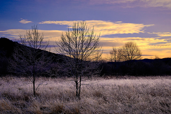 Cades Cove at sunrise.  The cove is in a bowl and is surrounded by high hills all around.