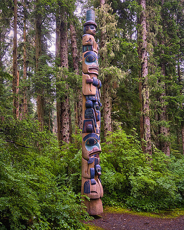 The totem poles are authentic Tlingit and Haida monumental carvings displayed along the scenic rainforest trails.