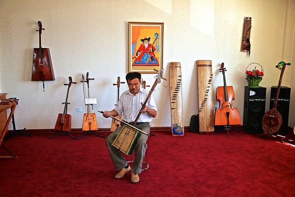 The owner of the Horse-Head Fiddle Factory plays his original 2-string fiddle.