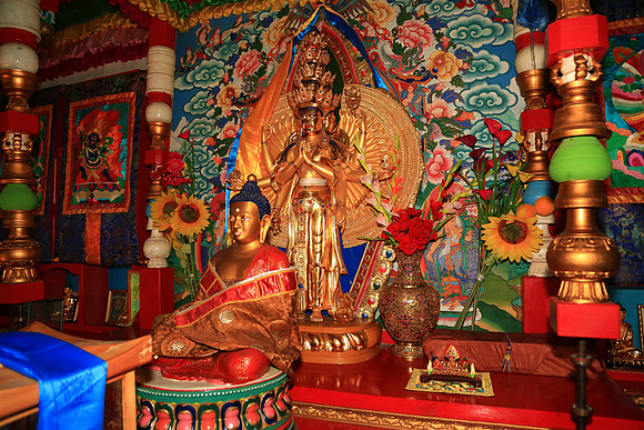Paintings and wall hangings portray Buddhist teachings along with sacred symbols, money offerings, and prayers wrapped in orange cloth.