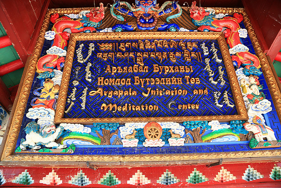 Four different alphabets cover this sign. Along the left and right reading from top to bottom swirls the Classical Mongol Script.