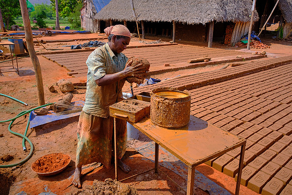 Clay mud is packed into brick making molds.