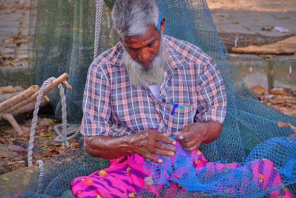 Fisherman repairs fishing net, Kochi, India.