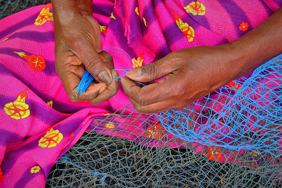 Fisherman repairs fishing net, Kochi, India.