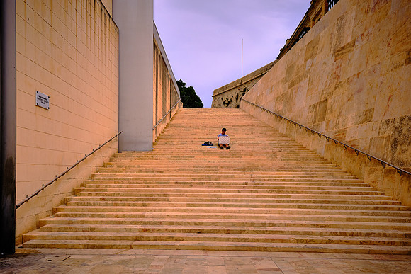 Lone artist sitting by the City Gate of Valletta, a UNESCO World Heritage Site.
