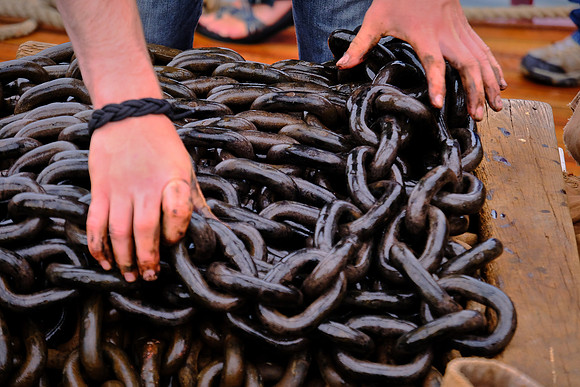 Deckhand furls anchor chain, Windjammer Angelique, Camden, Maine