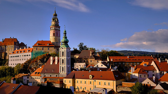 Český Krumlov town, castle, tower, and St. Jost Church at sunset.