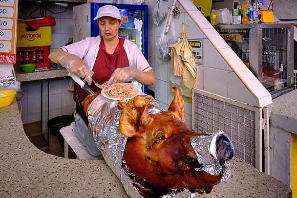 Rice and corn are served with pulled pork after cooking inside a whole pig in a local market.