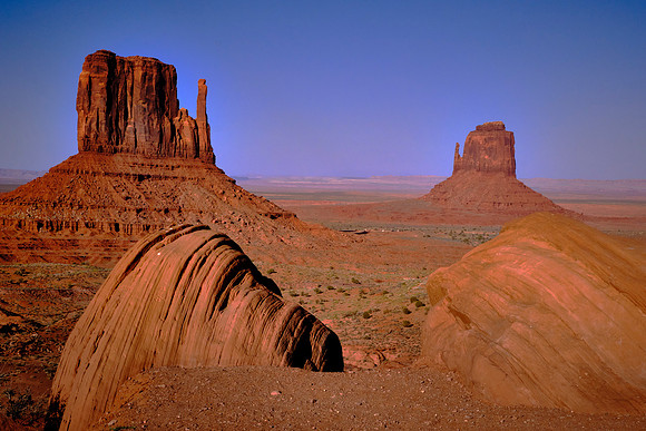 Monument Valley, UT.  West and East Mitten Buttes with Ansel Adams rocks in the foreground at sunset. Ansel Adams took a photograph of the mittens in 1958 from this location.