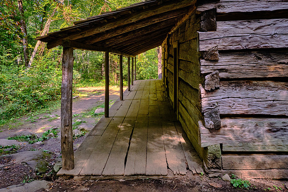 The cabin has a covered porch that spans both sides of the house.